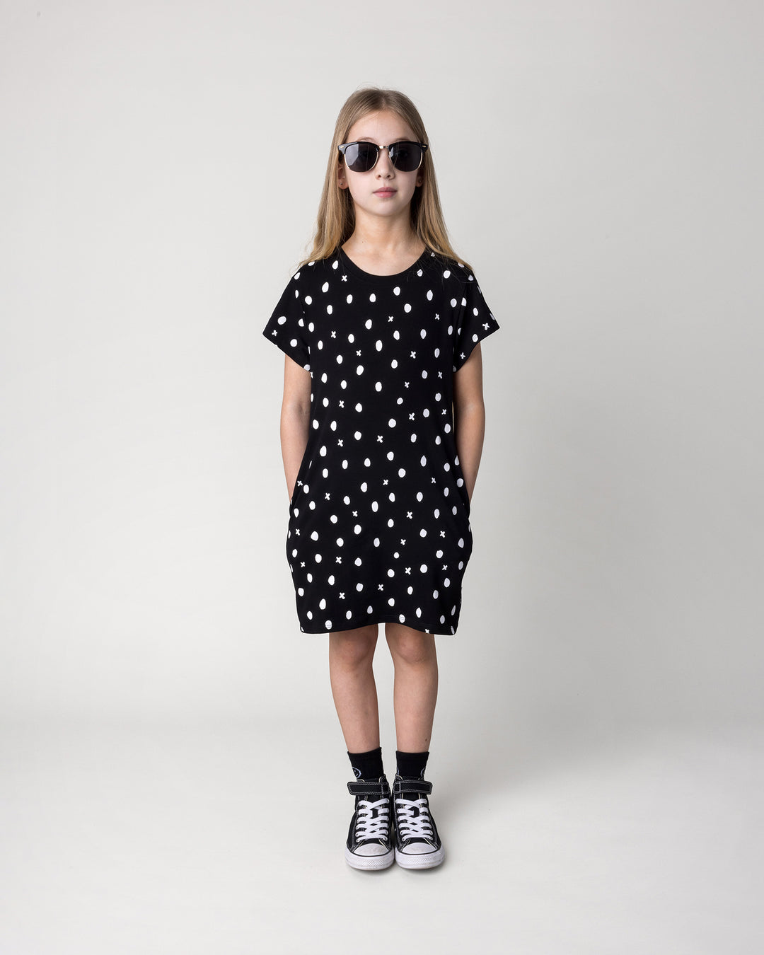 Kid wearing the Spotty Dress in black, front view