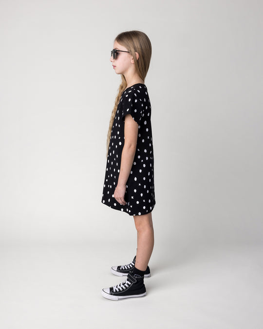 Kid wearing the Spotty Dress in black, side view