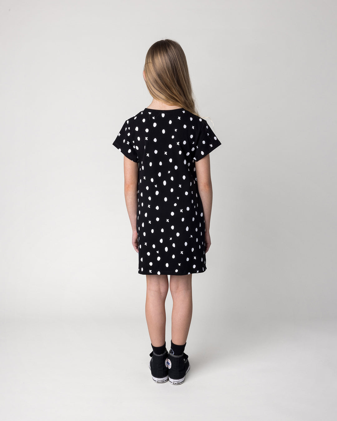 Kid wearing the Spotty Dress in black, back view
