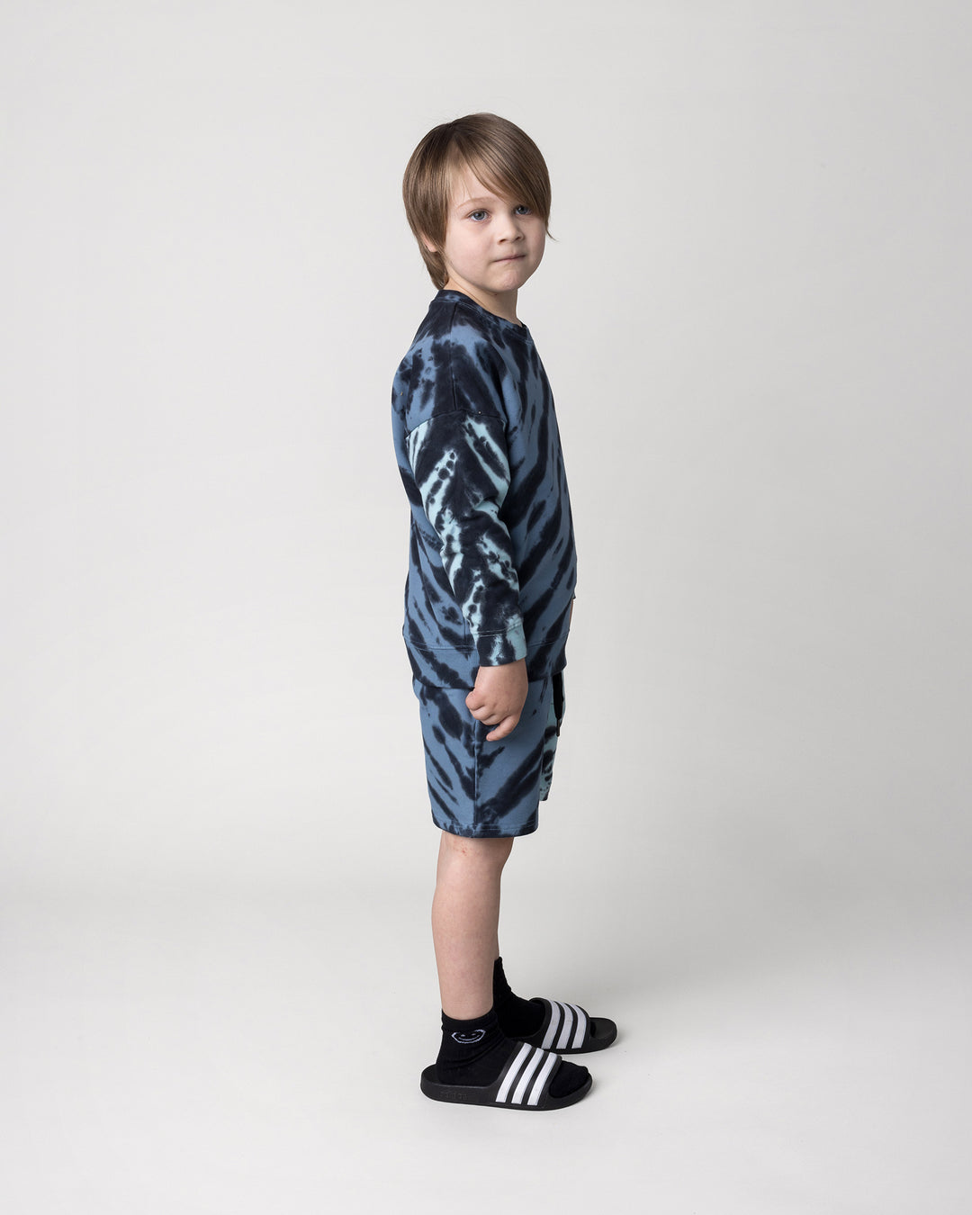 Kid wearing the Duo Tie Dye Crew in blue and aqua with the Duo Tie Dye Short in blue and aqua, side view