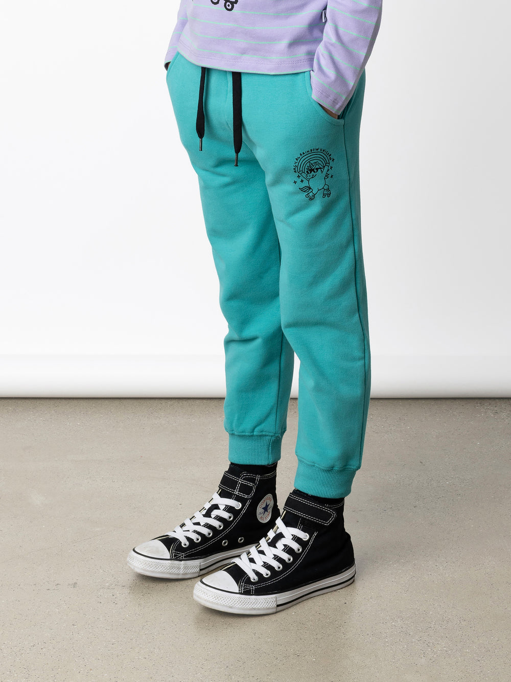 Minti kids clothing. Relaxed fit trackies with cosy side pockets, elasticated waistband, shoelace cord and 2x2 Rib cuffs. Small Magical Rainbow Unicorn print on the front. 330 Gram // Brushed Inside // 95% Cotton // 5% Elastane.
