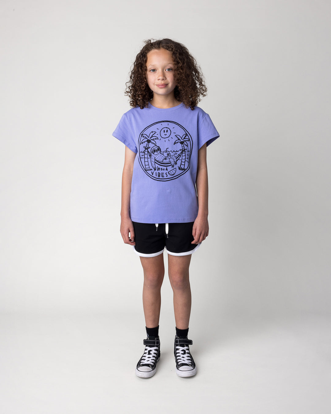 Kid wearing the Sprint Short in black and white with the Chill Sloth Tee in purple, front view