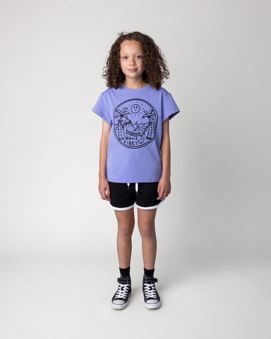 Kid wearing the Sprint Short in black and white with the Chill Sloth Tee in purple, front view