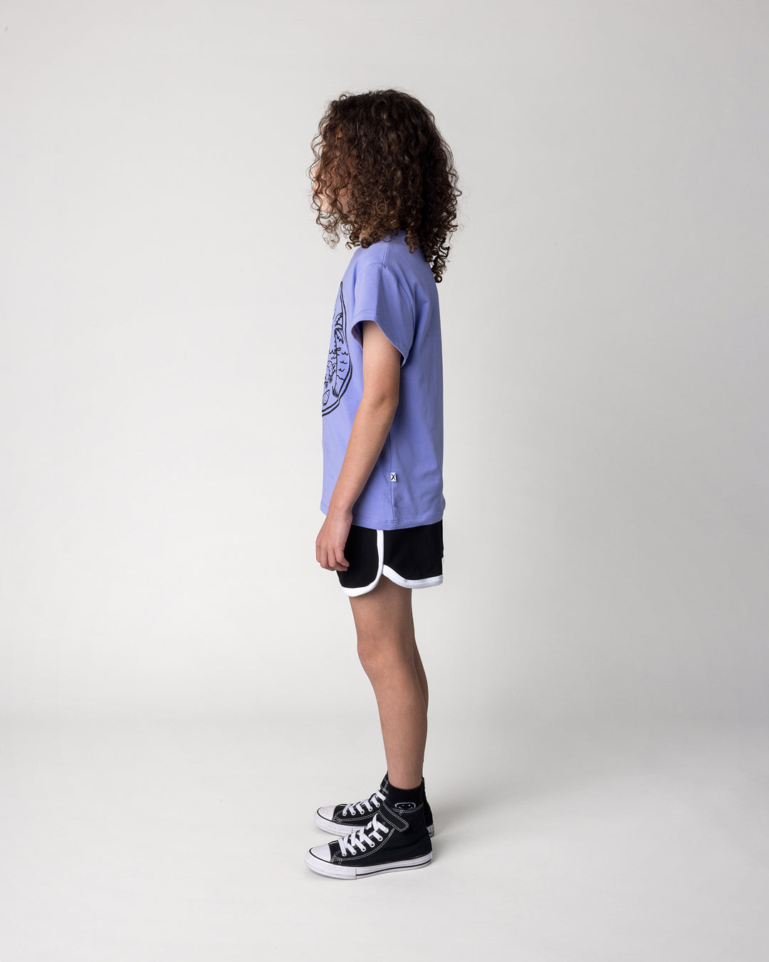 Kid wearing the Sprint Short in black and white with the Chill Sloth Tee in purple, side view