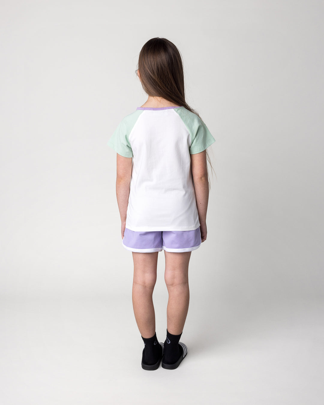 Kid wearing the Sprint Short in lilac and white with the Skate Cactus Tee in white and mint, back view