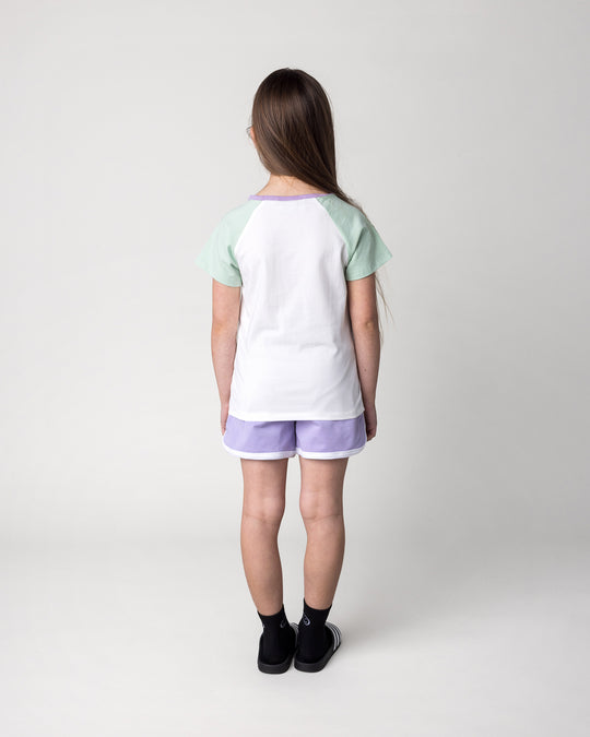 Kid wearing the Sprint Short in lilac and white with the Skate Cactus Tee in white and mint, back view