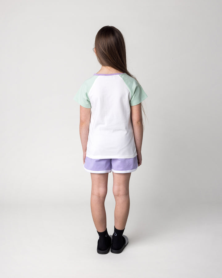 Kid wearing the Sprint Short in lilac and white with the Skate Cactus Tee in white and mint, back view