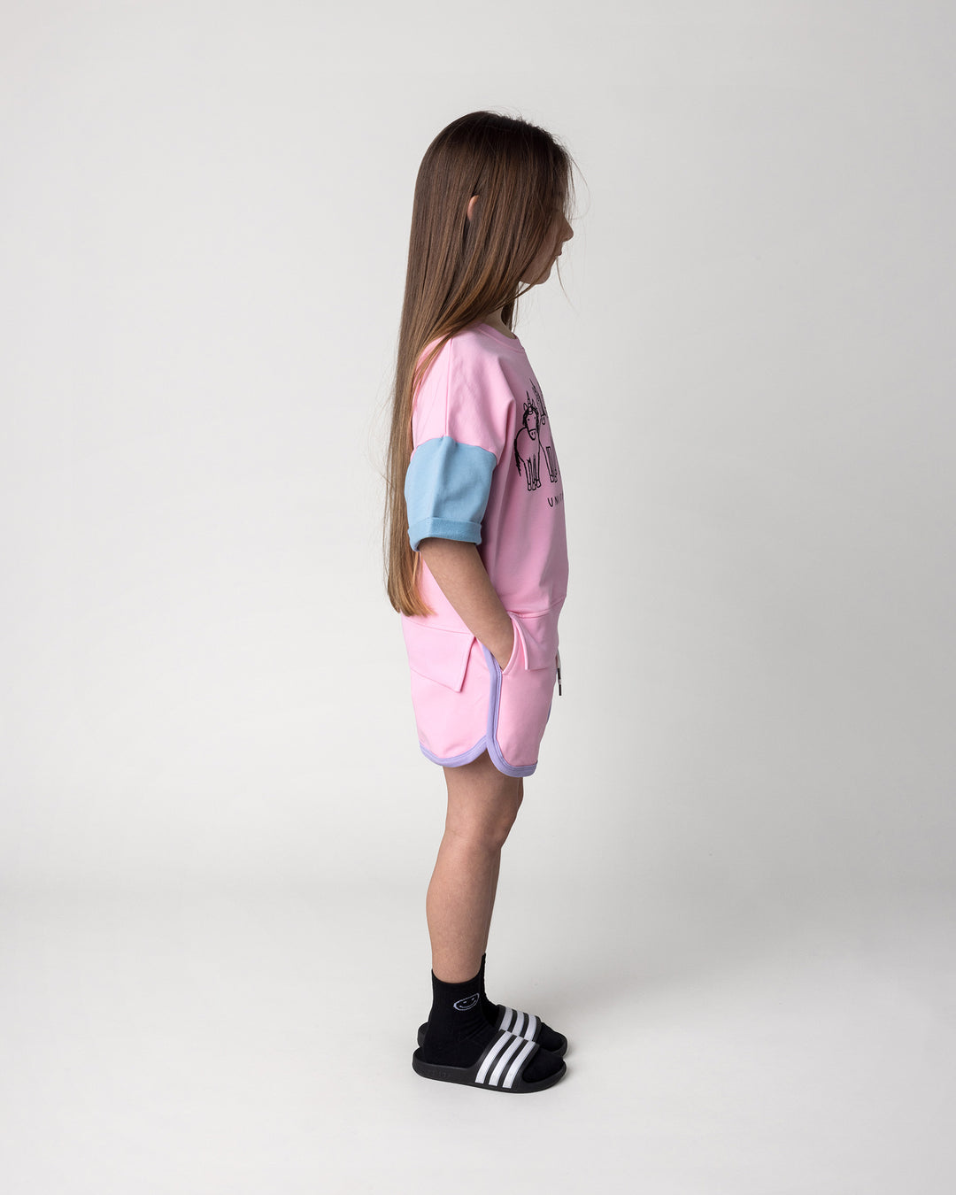 Kid wearing the Sprint Short in pink, purple and aqua with the Unicorn Club Short Sleeve Crew in pink, purple and aqua, side view
