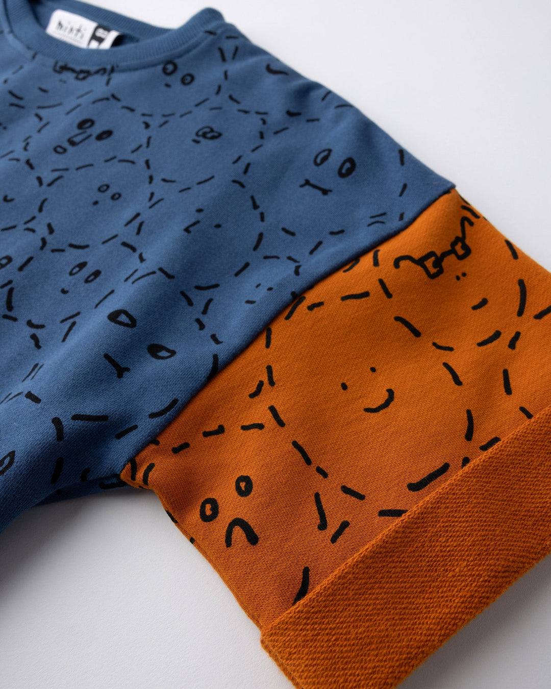 Close up detail of the Different Faces Short Sleeve Crew in navy, grey marle and orange