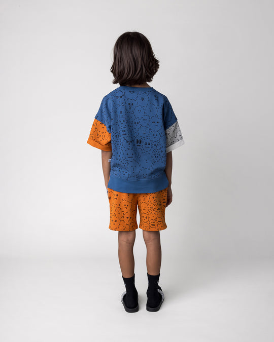 Kid wearing the Different Faces Short Sleeve Crew in navy, grey marle and orange with the Different Faces Short in burnt orange, back view
