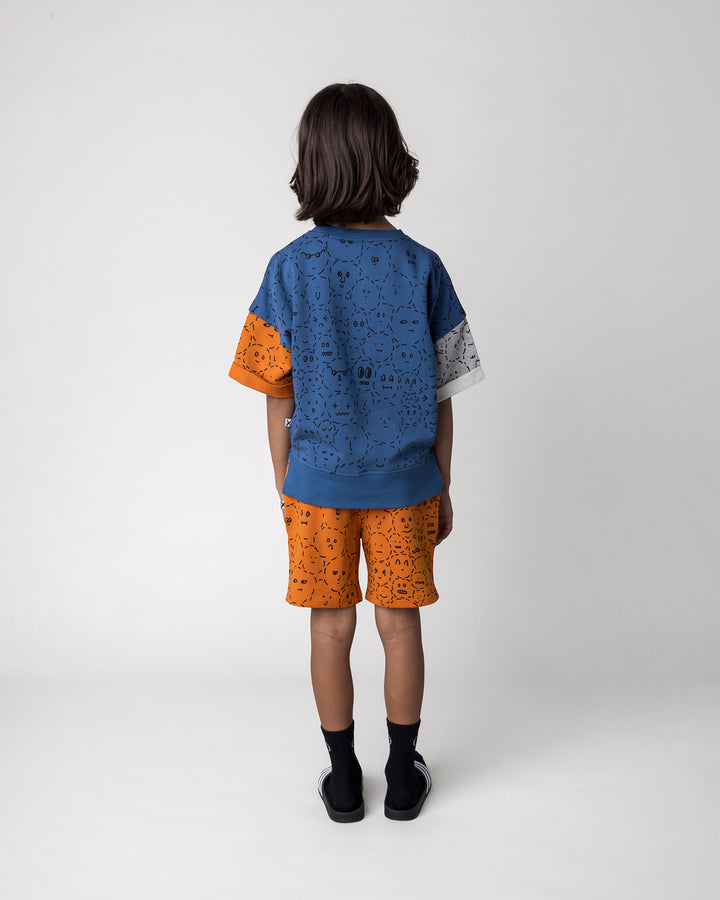 Kid wearing the Different Faces Short Sleeve Crew in navy, grey marle and orange with the Different Faces Short in burnt orange, back view