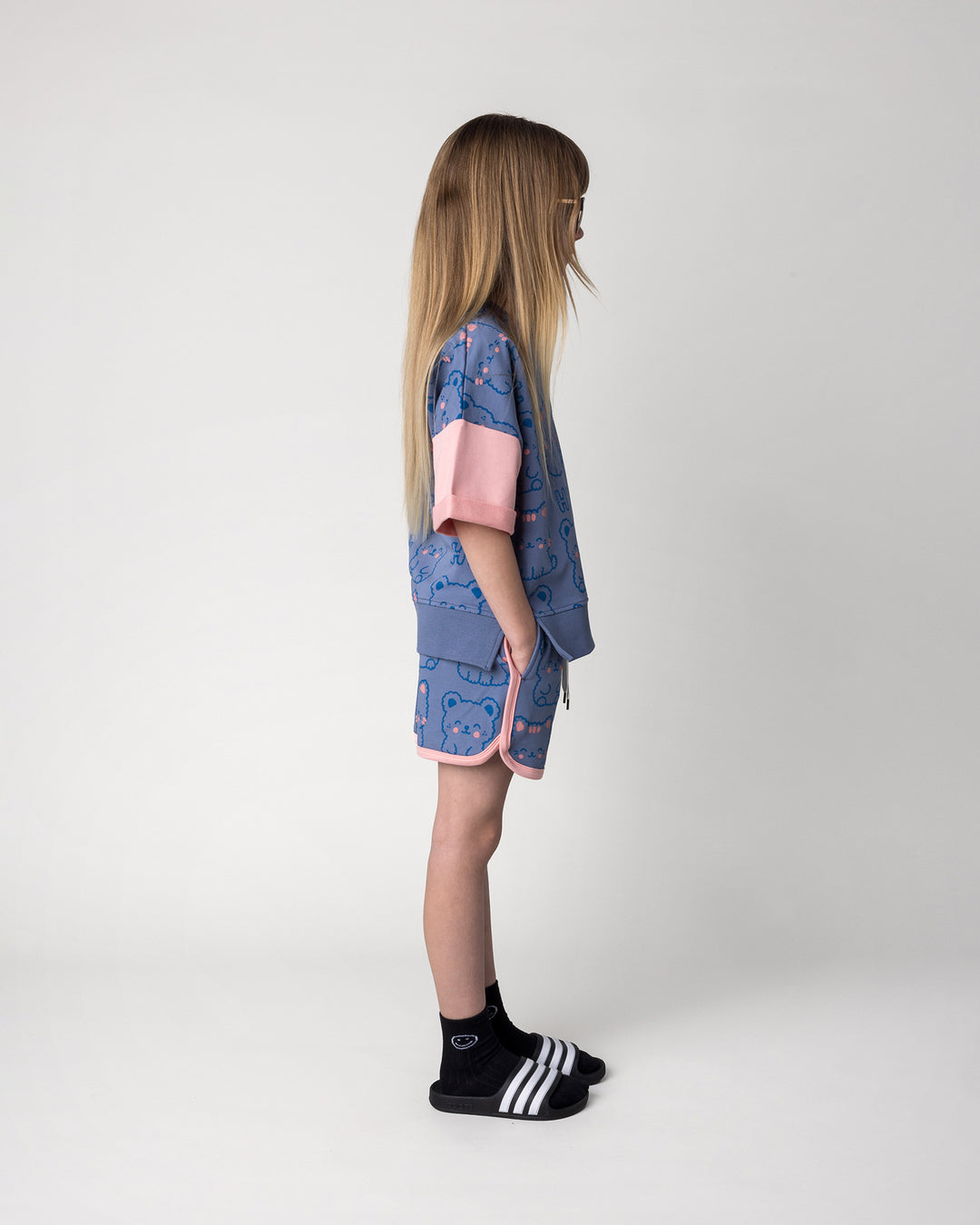 Kid wearing the Hi Cat Bear Short Sleeve Crew in cornflower and pink with the Hi Cat Bear Short in cornflower and pink, side view