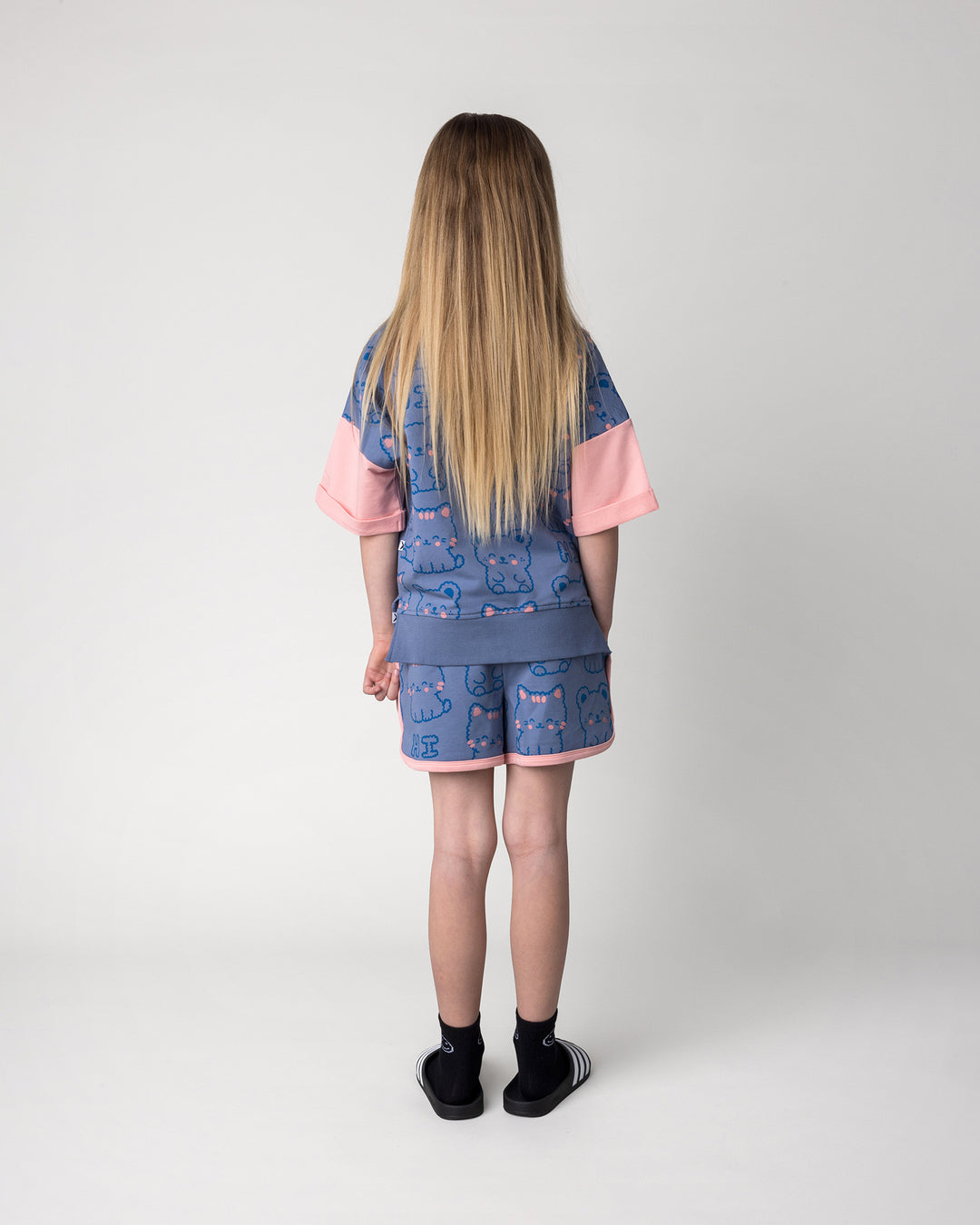 Kid wearing the Hi Cat Bear Short Sleeve Crew in cornflower and pink with the Hi Cat Bear Short in cornflower and pink, back view