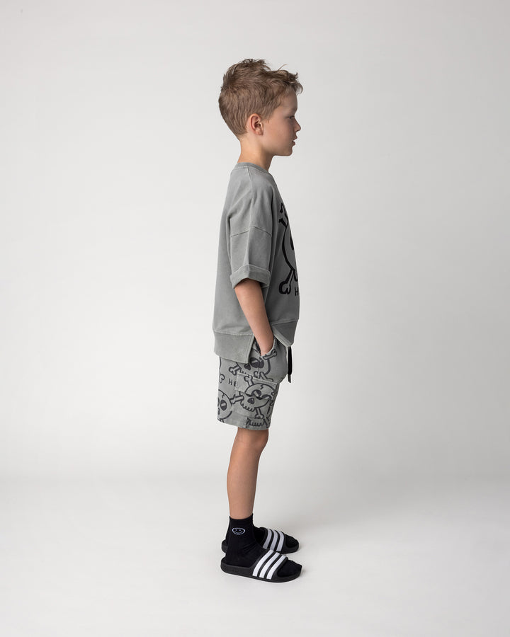 Kid wearing the Hello Skull Short Sleeve Crew in grey wash with the Hello Skull Short in grey wash, side view
