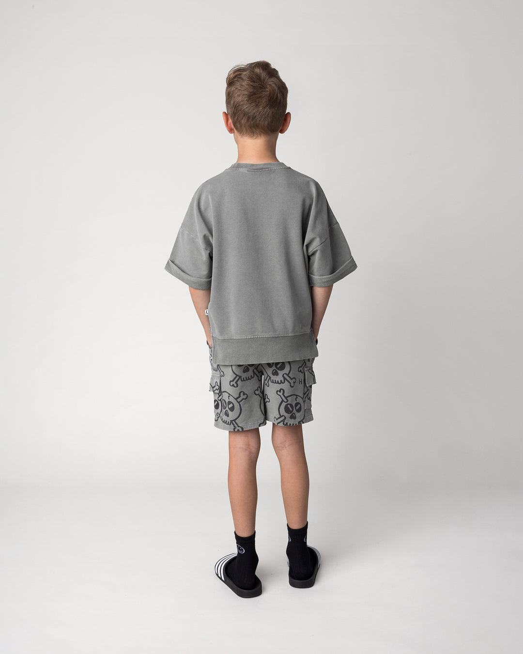 Kid wearing the Hello Skull Short Sleeve Crew in grey wash with the Hello Skull Short in grey wash, back view