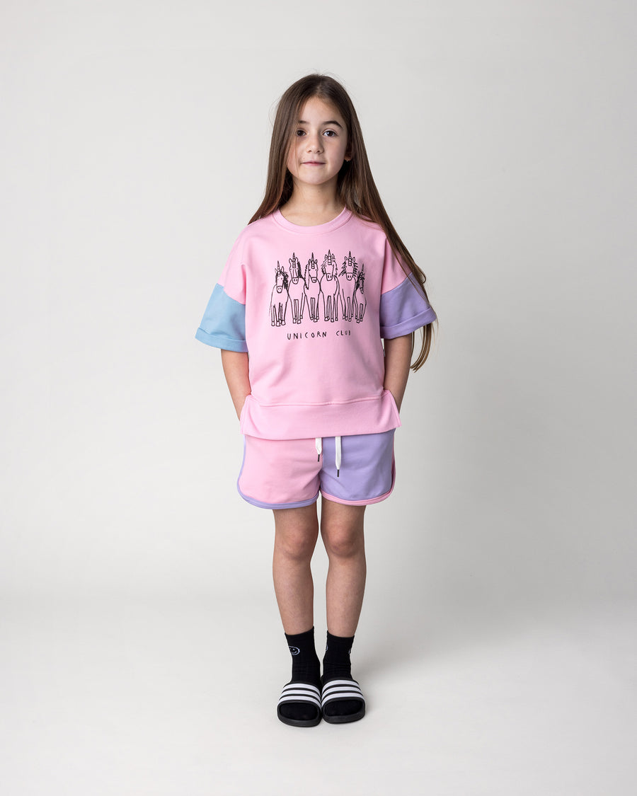 Kid wearing the Unicorn Club Short Sleeve Crew in pink, purple and aqua with the Sprint Short in pink, purple and aqua, front view