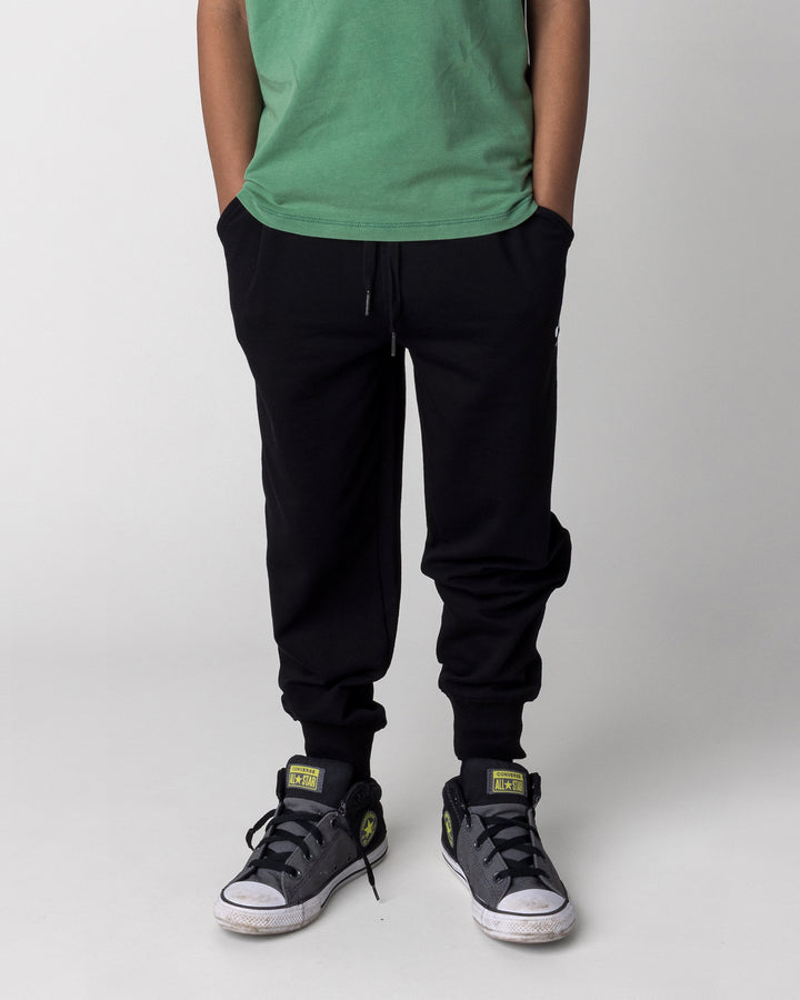 Kid wearing the Studio Trackies in black, front view close up