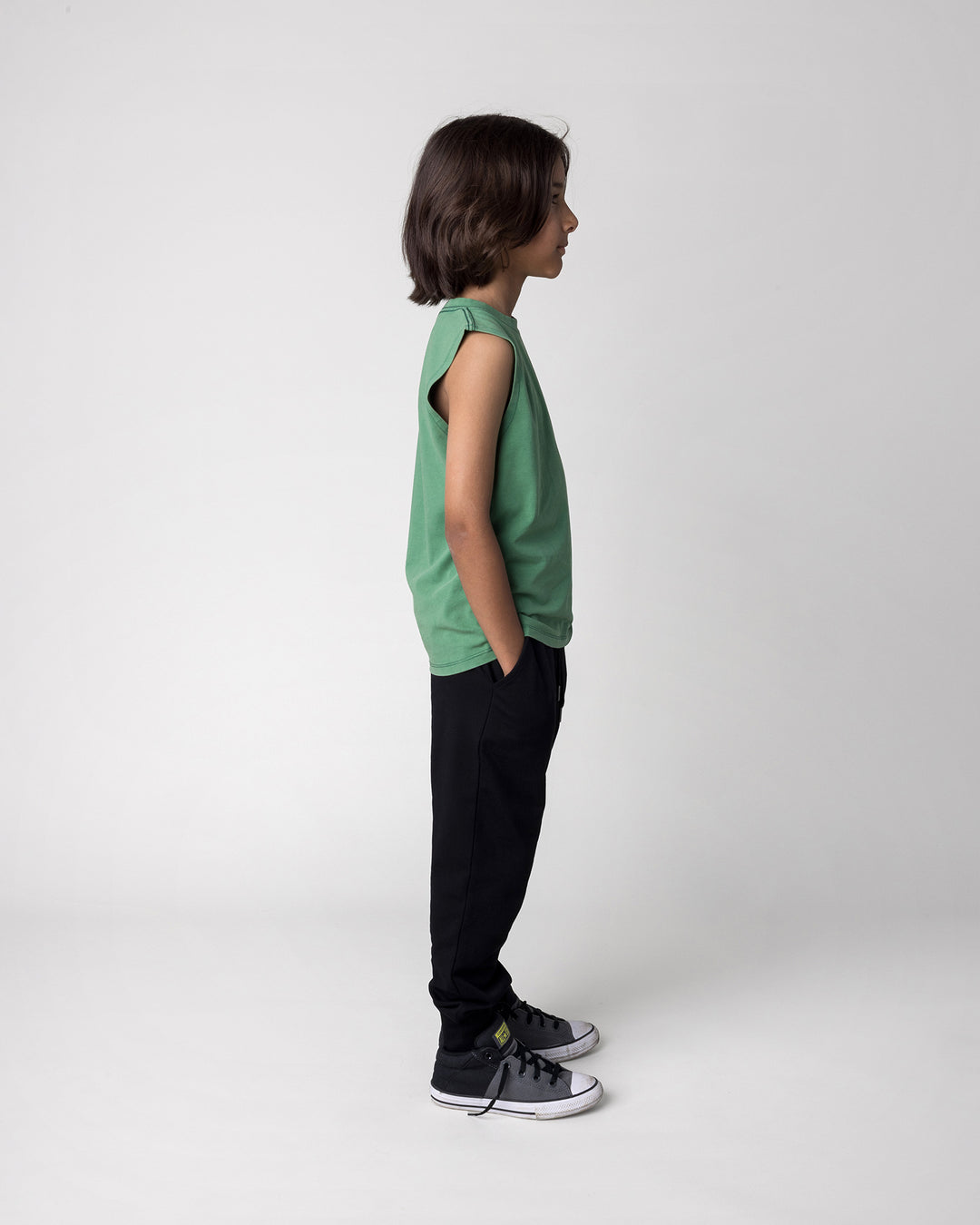 Kid wearing the Studio Trackies in black with the Hi Pigeon Sleeveless Tee in turf wash, side view