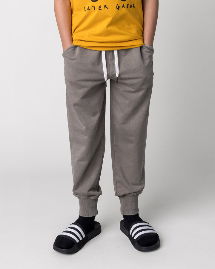 Kid wearing the Blasted Studio Trackies in grey wash, front view close up
