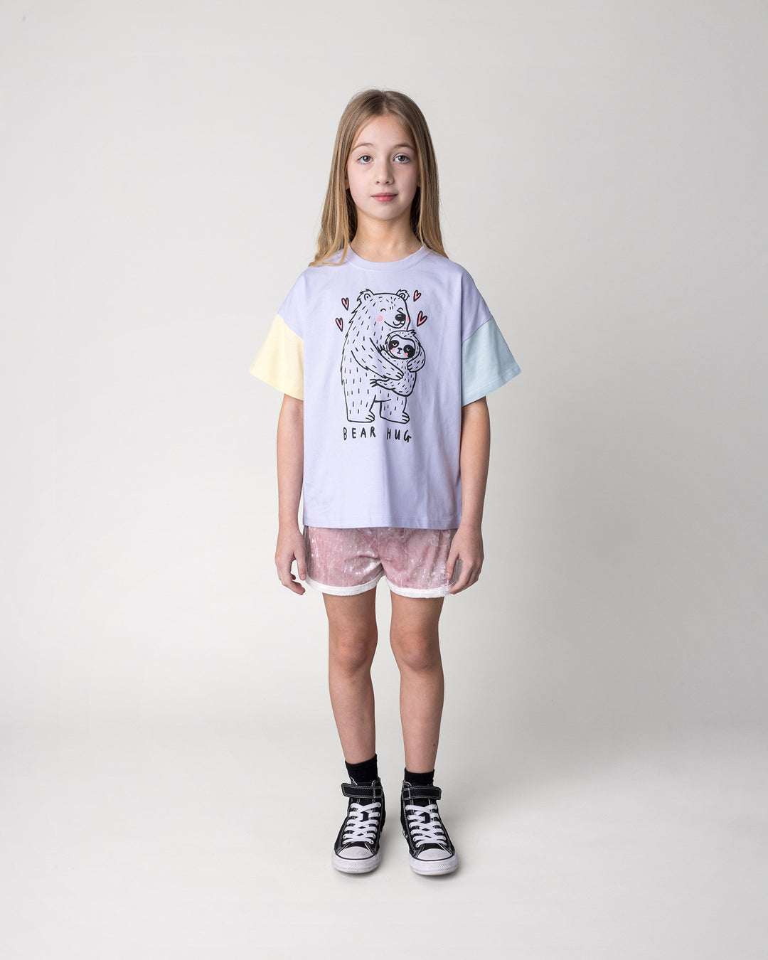 Kid wearing the Bear Hug Tee in lilac, lemon and blue with the Velvet Runner Short in blush and cream, front view