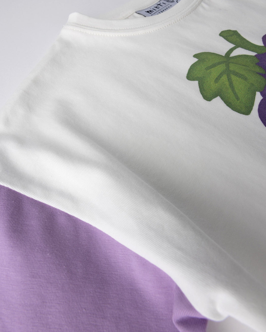 Close up detail of the Biking Grape Tee in white, purple and green