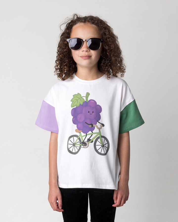 Close up of the Biking Grape Tee in white, purple and green on a kid, front view