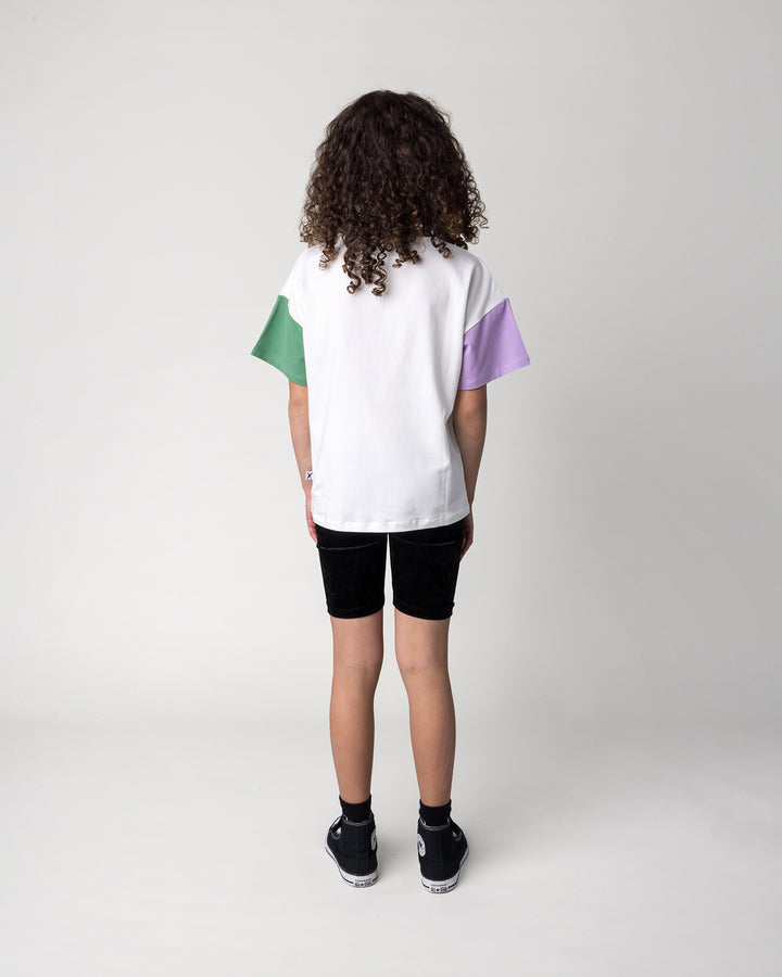 Kid wearing the Biking Grape Tee in white, purple and green with the Velvet Bike Pant in black, back view