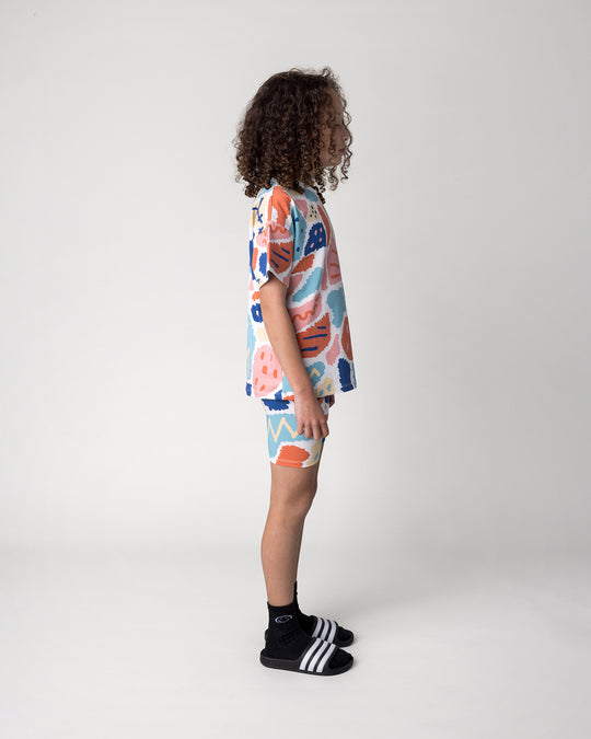 Kid wearing the Cool Shapes Tee in white with the Cool Shapes Bike Pant in white, side view