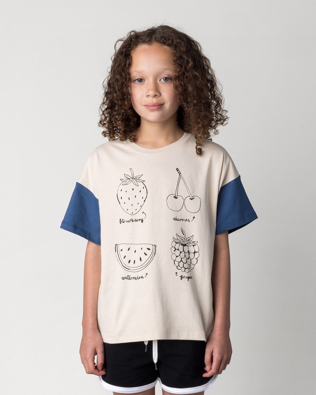 Close up of the Different Fruits Tee in stone and midnight on a kid, front view