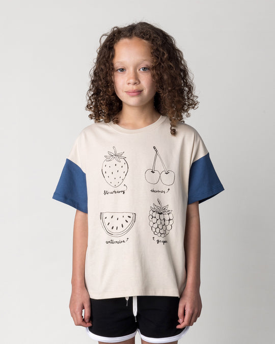 Close up of the Different Fruits Tee in stone and midnight on a kid, front view