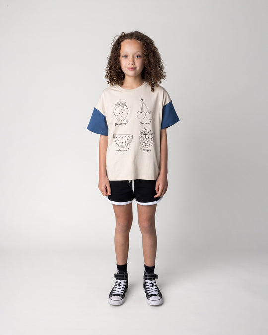 Kid wearing the Different Fruits Tee in stone and midnight with the Sprint Short in black and white, front view