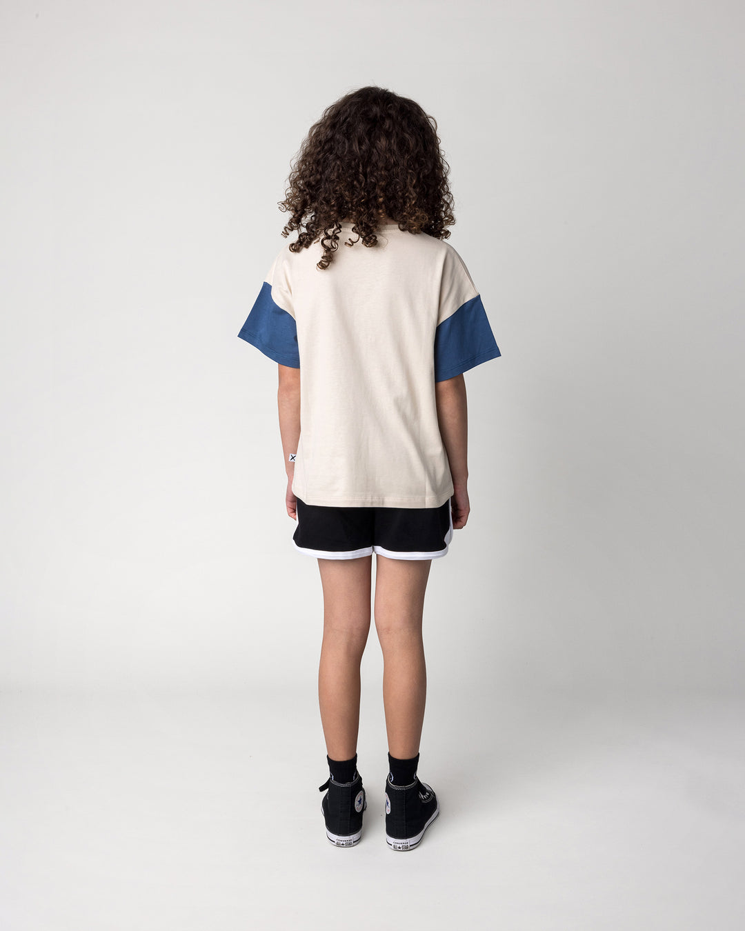 Kid wearing the Different Fruits Tee in stone and midnight with the Sprint Short in black and white, back view