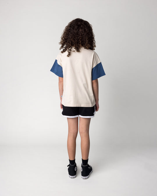 Kid wearing the Different Fruits Tee in stone and midnight with the Sprint Short in black and white, back view