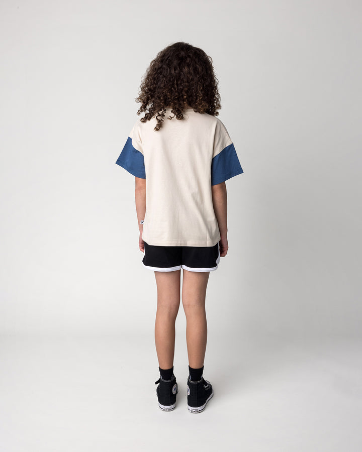 Kid wearing the Different Fruits Tee in stone and midnight with the Sprint Short in black and white, back view