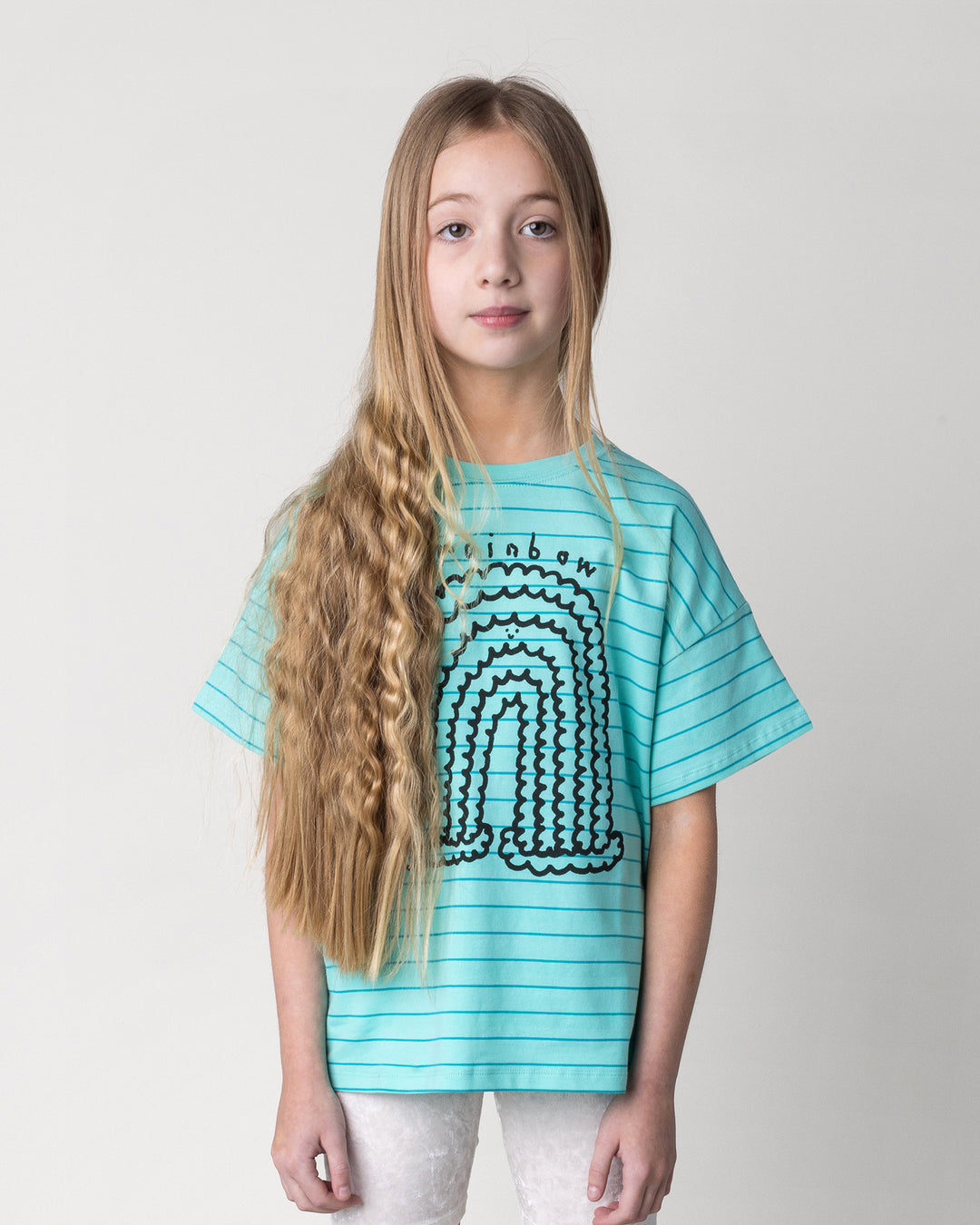Close up of the Happy Rainbow Tee in teal stripe on a kid, front view