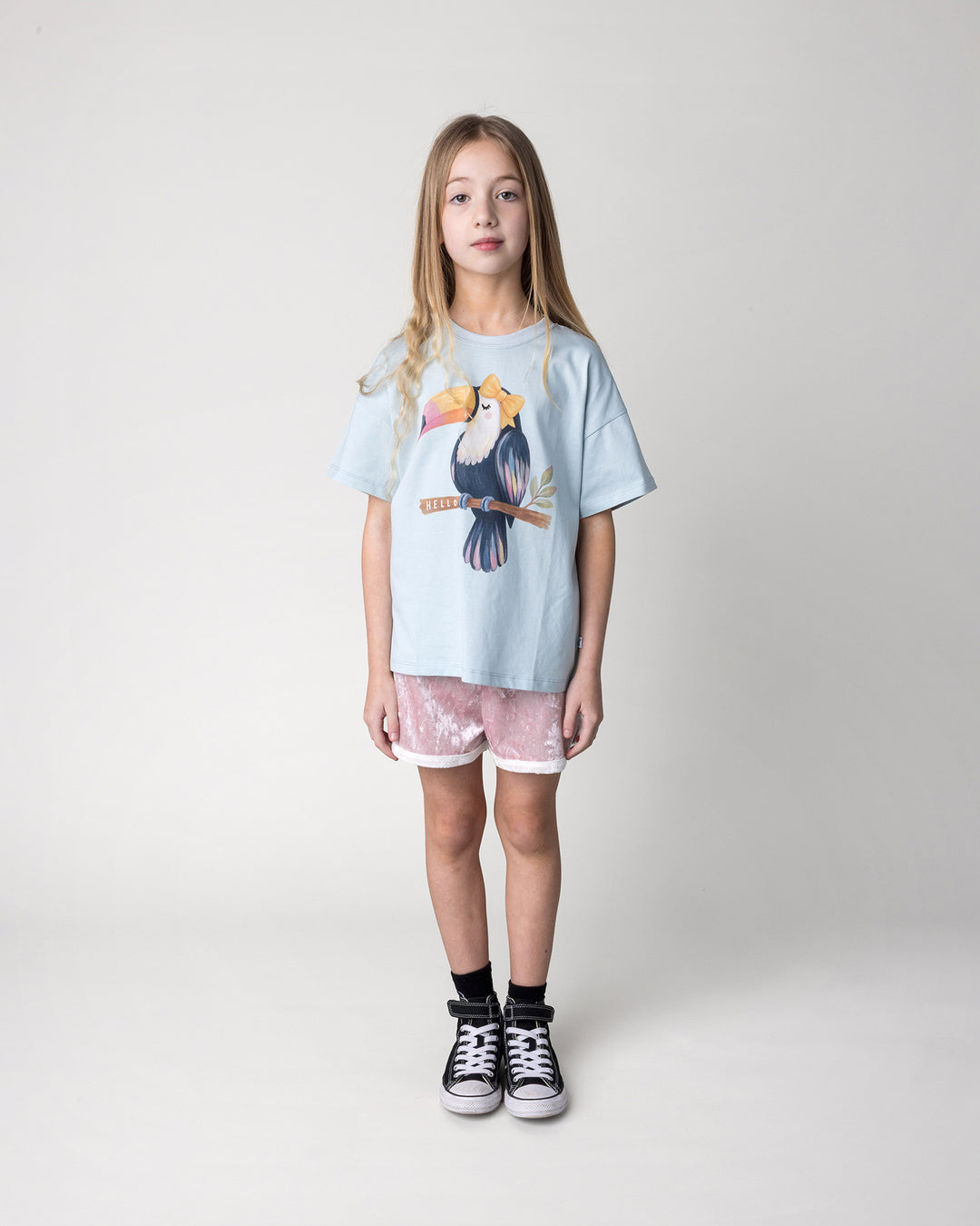 Kid wearing the Hello Toucan Tee in light blue with the Velvet Runner Short in blush and cream, front view