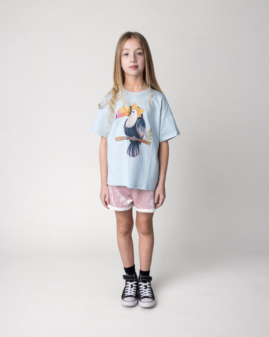 Kid wearing the Hello Toucan Tee in light blue with the Velvet Runner Short in blush and cream, front view