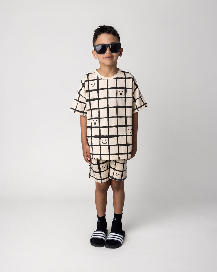 Kid wearing the Happy Squares Tee in beige with the Happy Squares Short in beige, front view