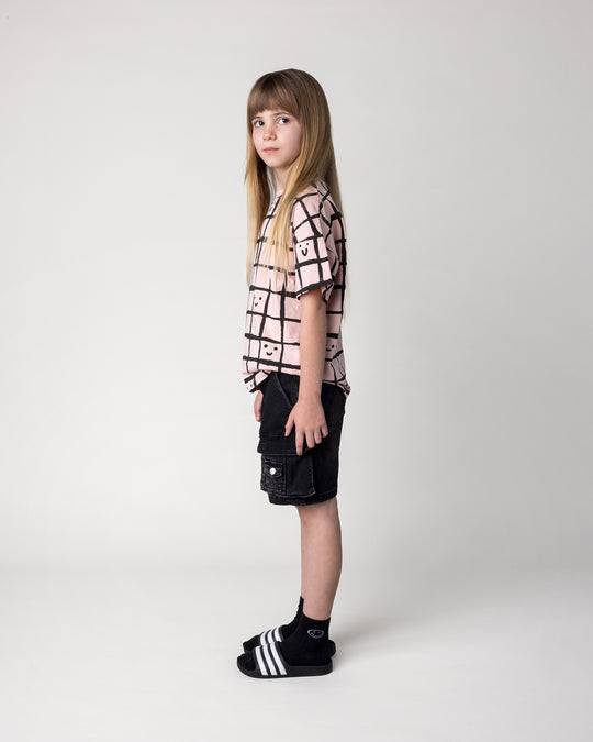 Kid wearing the Happy Squares Tee in dusty pink, side view