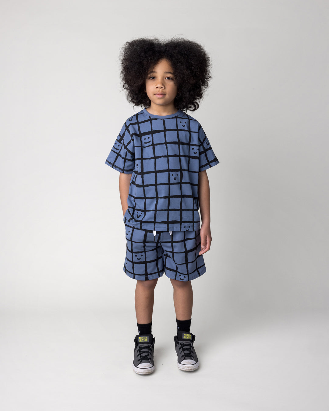 Kid wearing the Happy Squares Tee in muted blue with the Happy Squares Short in muted blue, front view