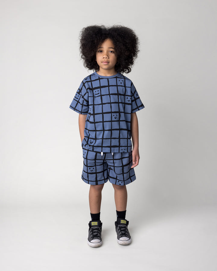 Kid wearing the Happy Squares Tee in muted blue with the Happy Squares Short in muted blue, front view