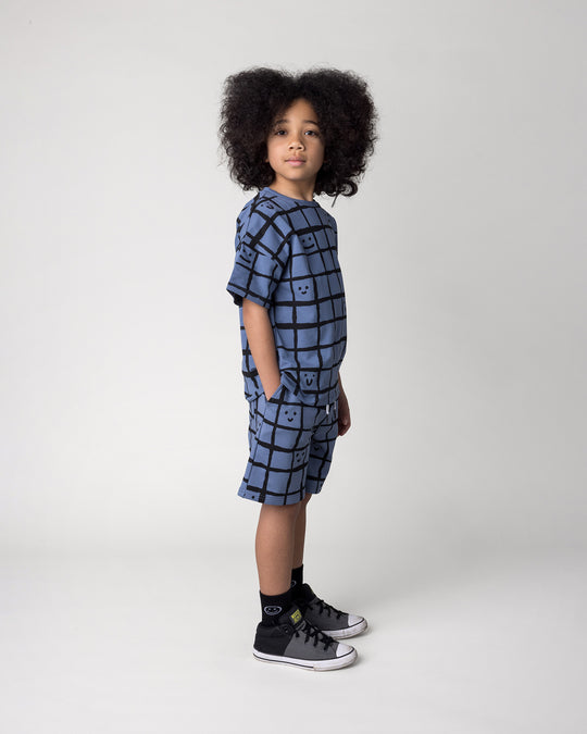 Kid wearing the Happy Squares Tee in muted blue with the Happy Squares Short in muted blue, side view