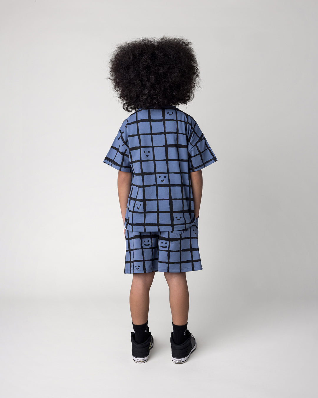 Kid wearing the Happy Squares Tee in muted blue with the Happy Squares Short in muted blue, back view