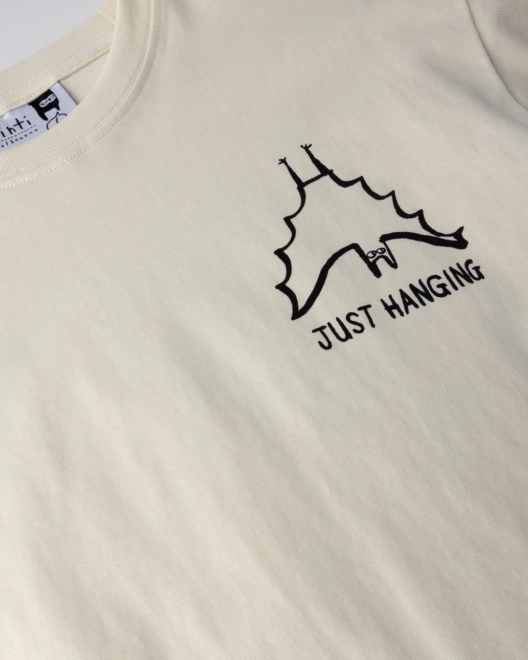 Close up of the Just Hanging Tee print in cream