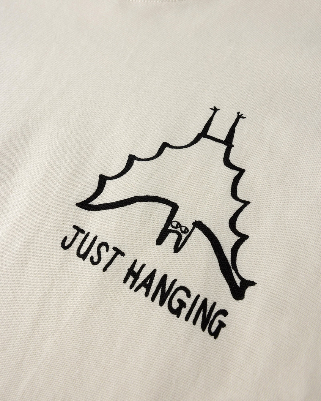 Close up of the Just Hanging Tee print in cream
