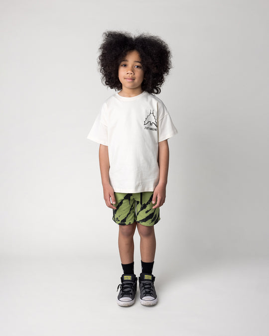 Kid wearing the Just Hanging Tee in cream with the Strike Short in lime, front view