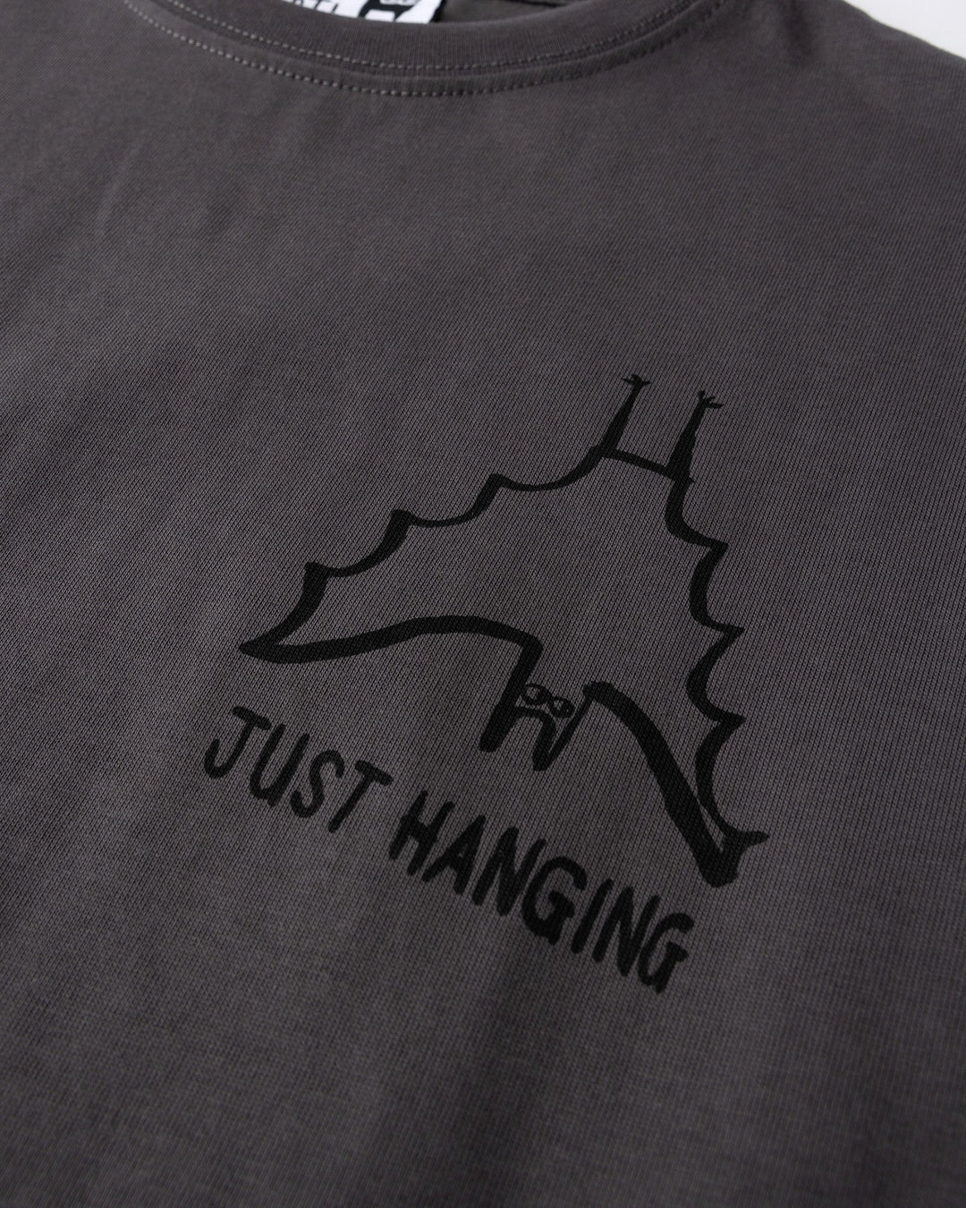 Close up of the Just Hanging Tee print in dark grey