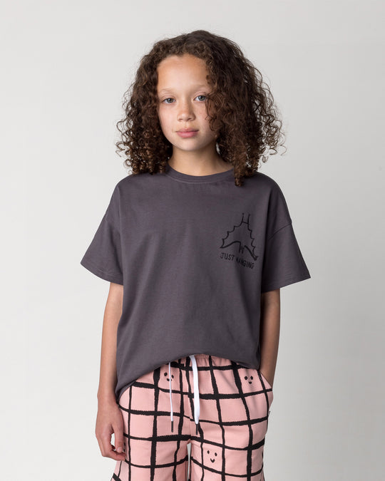 Close up of the Just Hanging Tee in dark grey on a kid, front view