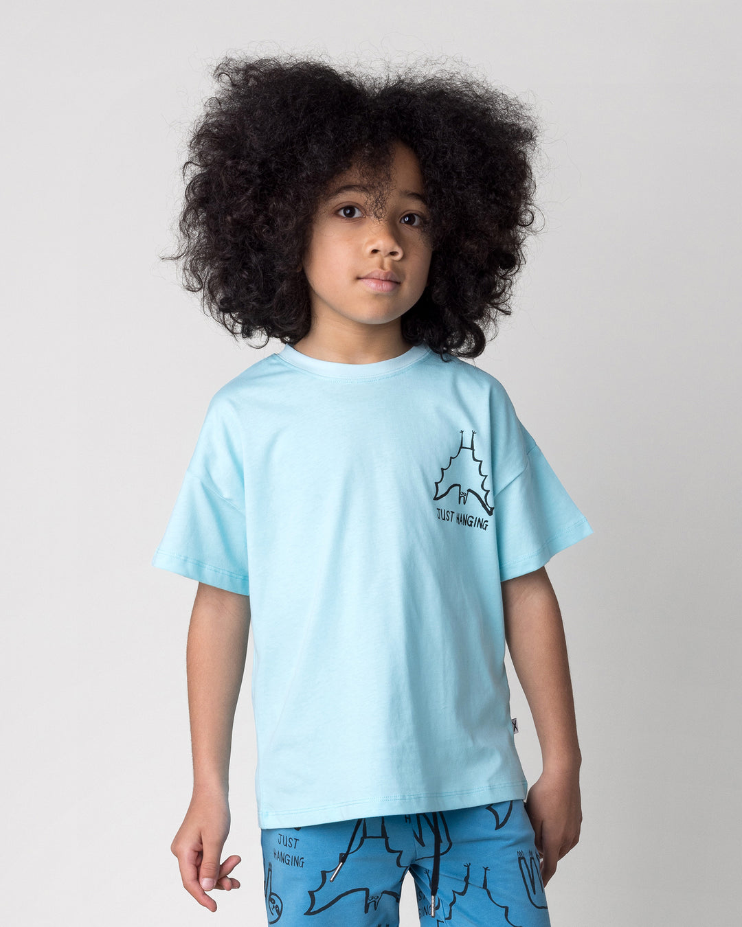 Close up of the Just Hanging Tee in light aqua on a kid, front view