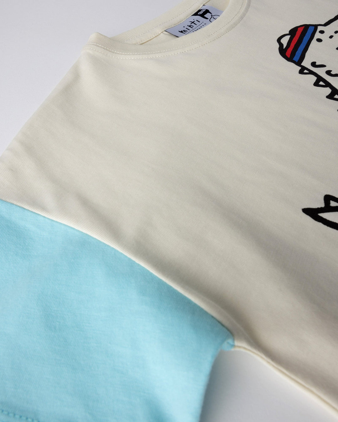 Close up detail of the Later Gator Tee in cream and blues